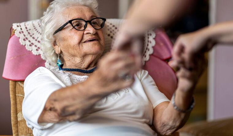 Elderlywoman holding hands with healthcare worker 