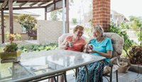 Two elderly women enjoy a cup of tea together.