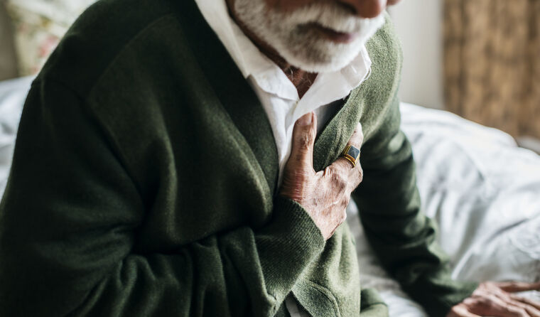 Elderly man clutching his chest.