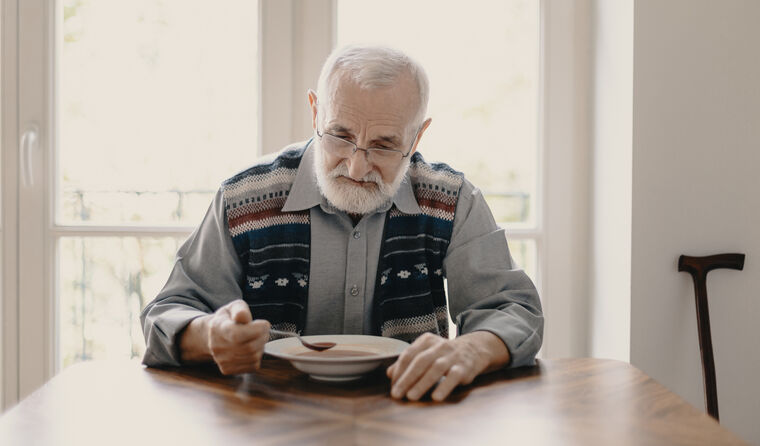 Old man alone eating soup.