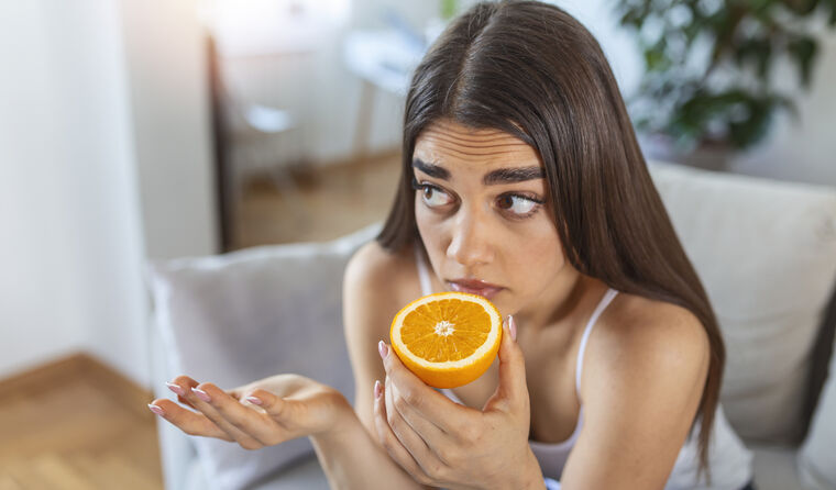 A young woman smelling an orange.