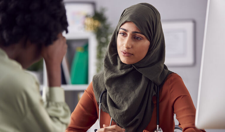 Female doctor in hijab with worried female patient