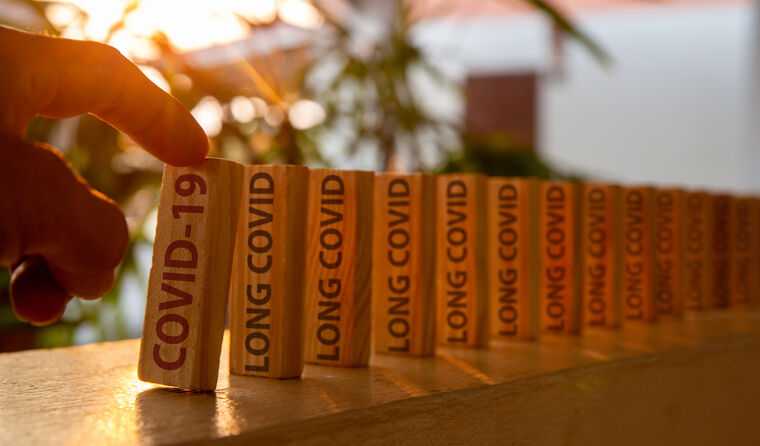 Long COVID written on a line of dominoes.