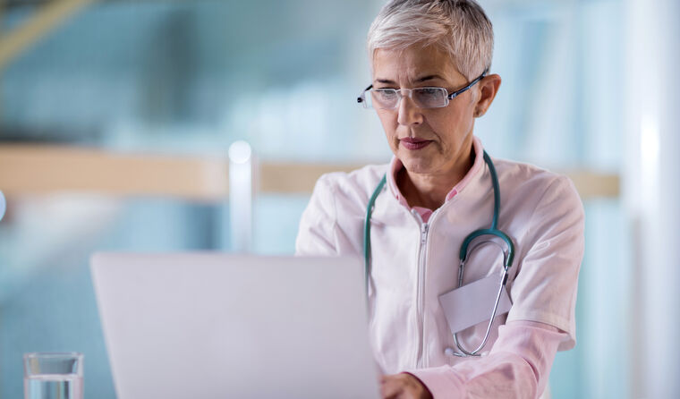 GP filling out survey on laptop