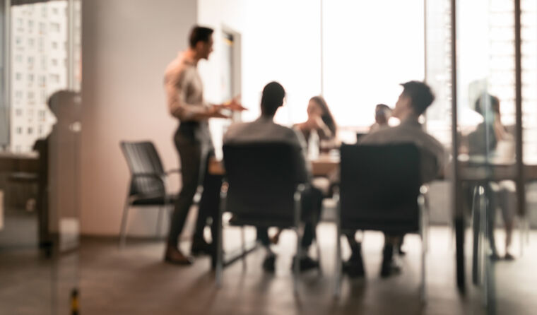 Blurred figures around a boardroom table.