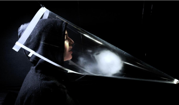 A person breathing into a Perspex cone.