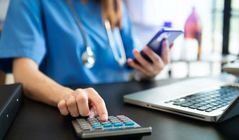 Female doctor in blue gown using a calculator