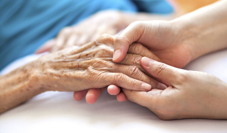 Someone holding hands with an elderly sick patient