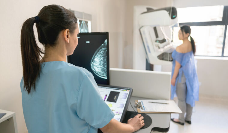 Female radiographer does mammogram on woman.