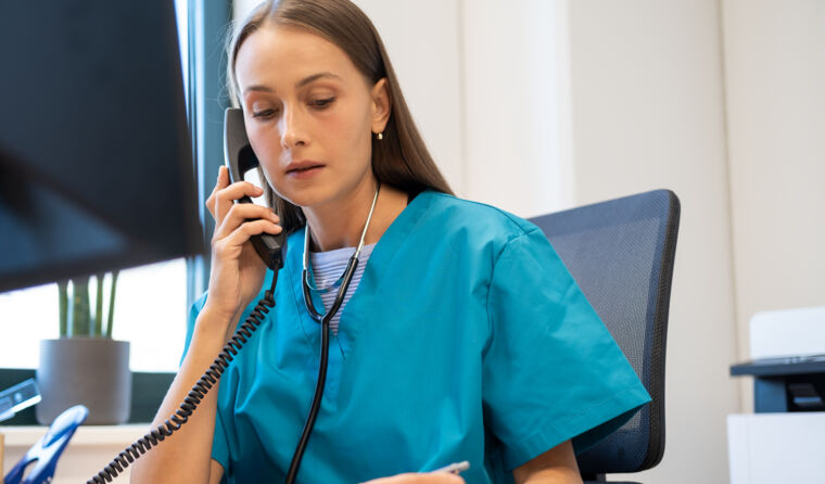 A female doctor making a phone call at her desk.