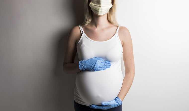 Pregnant woman wearing face mask and gloves.