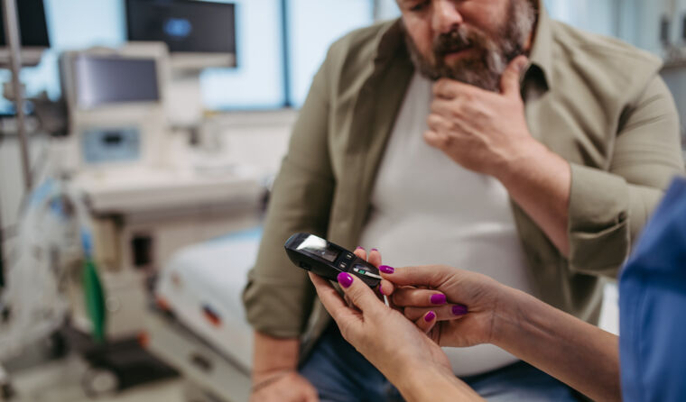 Overweight man is shown blood glucose monitor