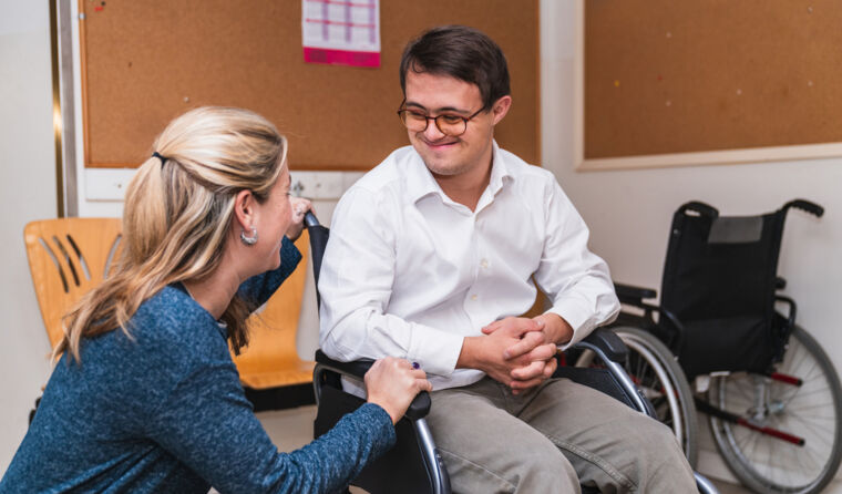 GP speaking to a patient sitting in a wheelchair.