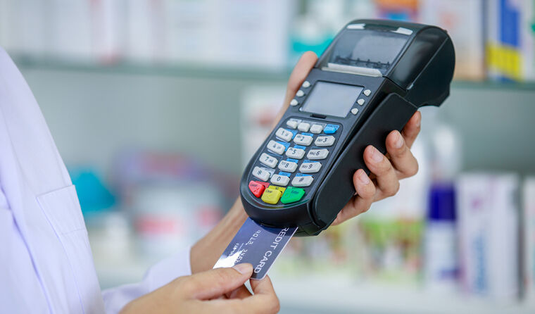 Pharmacist putting credit card into machine.