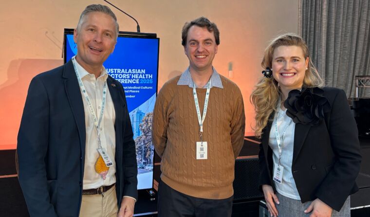 Two men and a woman smile for camera at conference