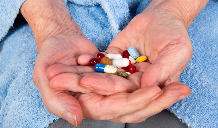 Close-up of hands holding various pills.