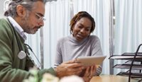 A GP shows a patient something on an iPad