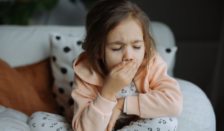 Young girl coughing in bed.