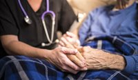 GP holding hand of elderly patient