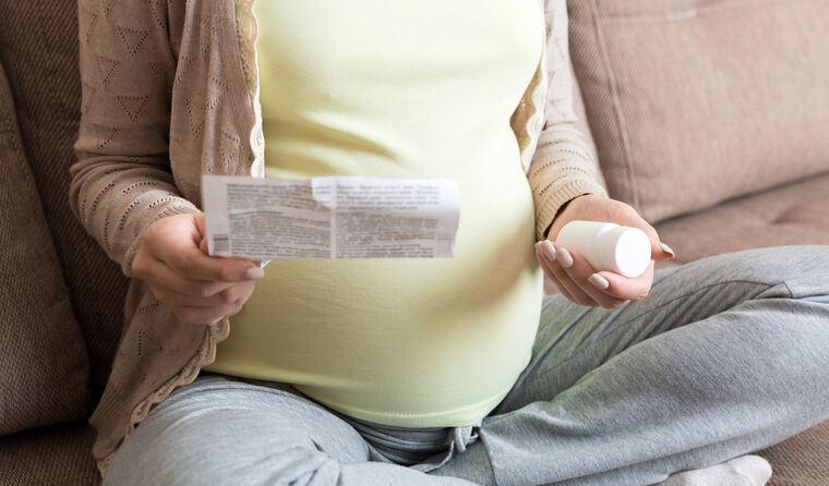 Pregnant woman reading medication instructions.
