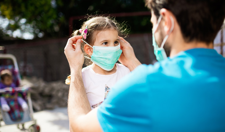 Parent putting face mask on child.