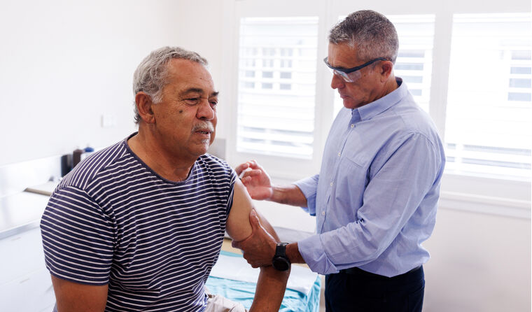Aboriginal man receives vaccine in his arm from GP