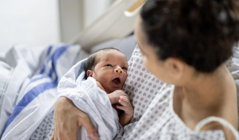 Mother holding newborn in hospital.