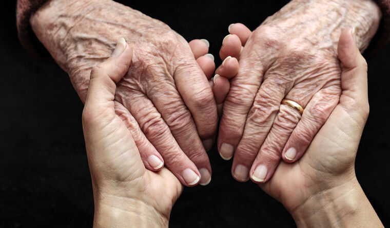 Older person's hands being held by younger person.