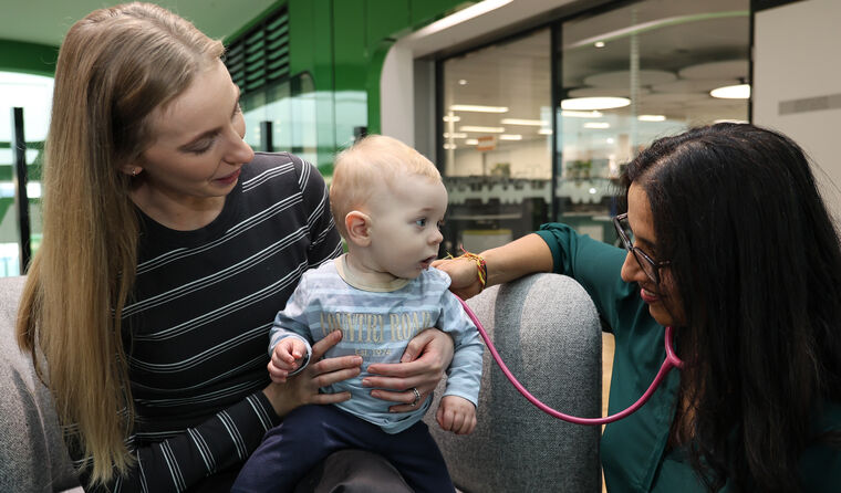 A women holding her baby next to a doctor.