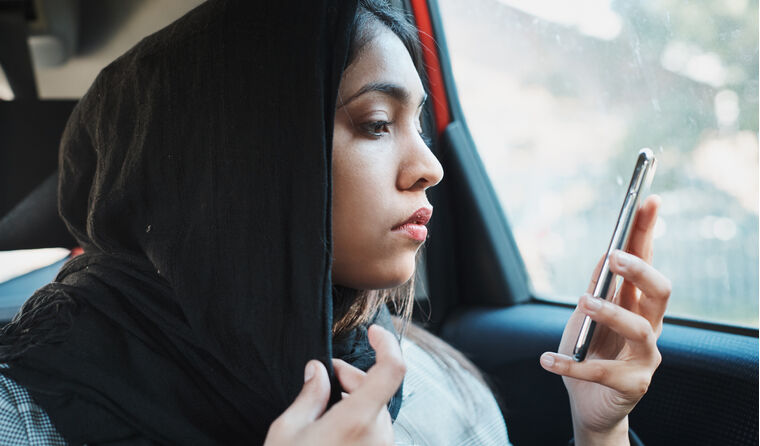 Young Muslim woman looking serious at phone