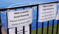 Sign on school fence promoting social distancing.