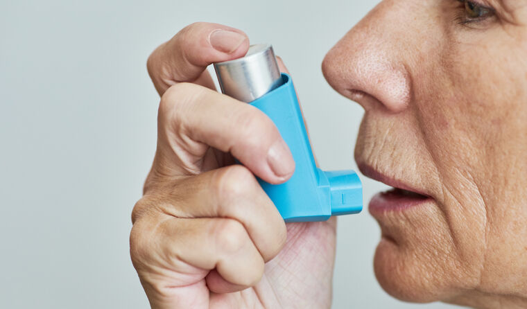 Closeup of senior woman using inhaler.