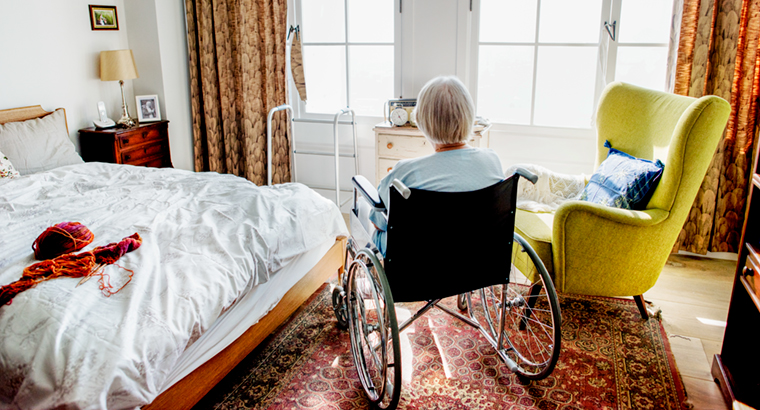 Older woman in wheelchair looking out window