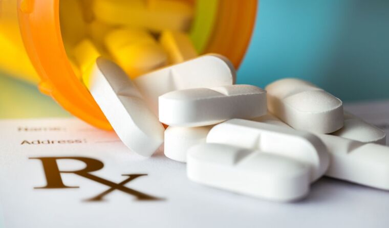 Pill bottle with white pills spilling out.