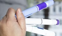 Person holding GLP-1 RA pens.