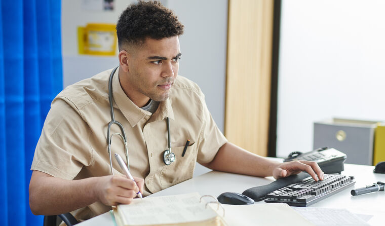 Young male GP working at computer