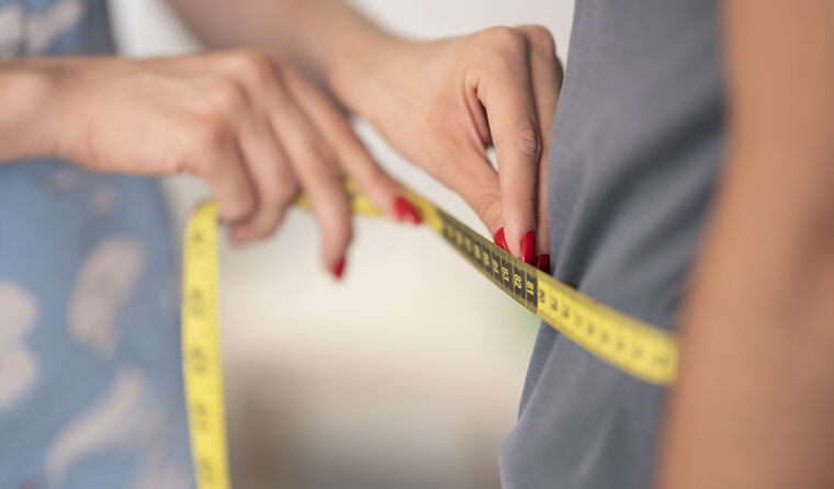 A doctor is measuring the circumference of a man's abdomen.