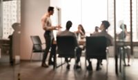 Blurred figures around a boardroom table.