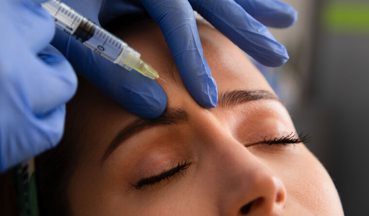 Woman receiving a Botox injection in forehead.