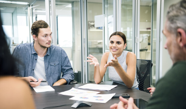 Young woman leads discussion around office table.