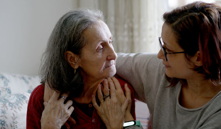 Middle-aged woman comforts elderly lady