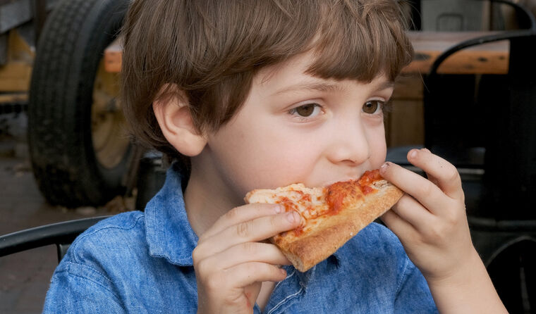 Little child boy having a slice of pizza.