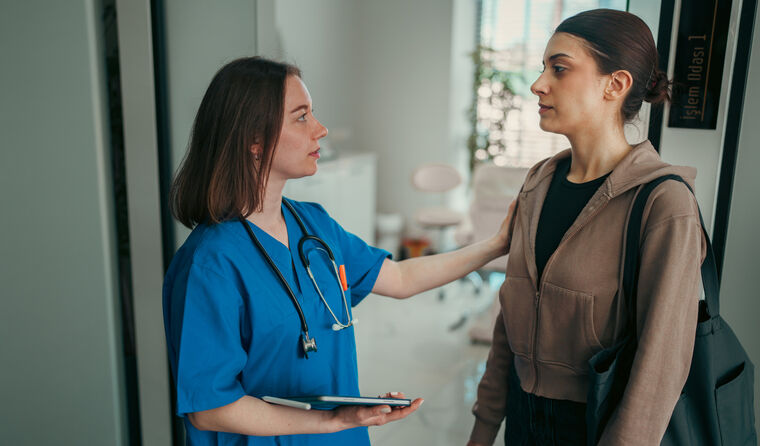 Young female doctor with hand on woman's shoulder 
