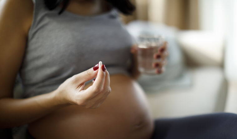 Pregnant woman holding a pill.