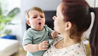 Mother holding sick, coughing baby