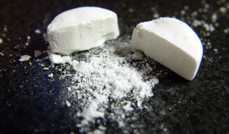 A white pill cut in half and crumbling.