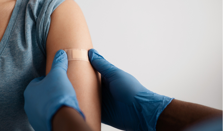A clinician placing a band-aid on a patient’s arm.