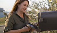 Middle-aged woman opens her letterbox.
