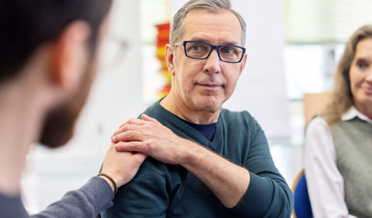 Person touching another man's shoulder.