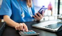 Female doctor in blue gown using a calculator